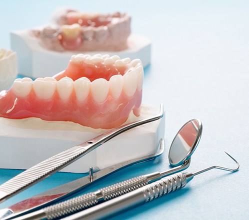 Set of dentures on a cast next to dental instruments