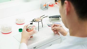 Lab technician in white shirt building dentures