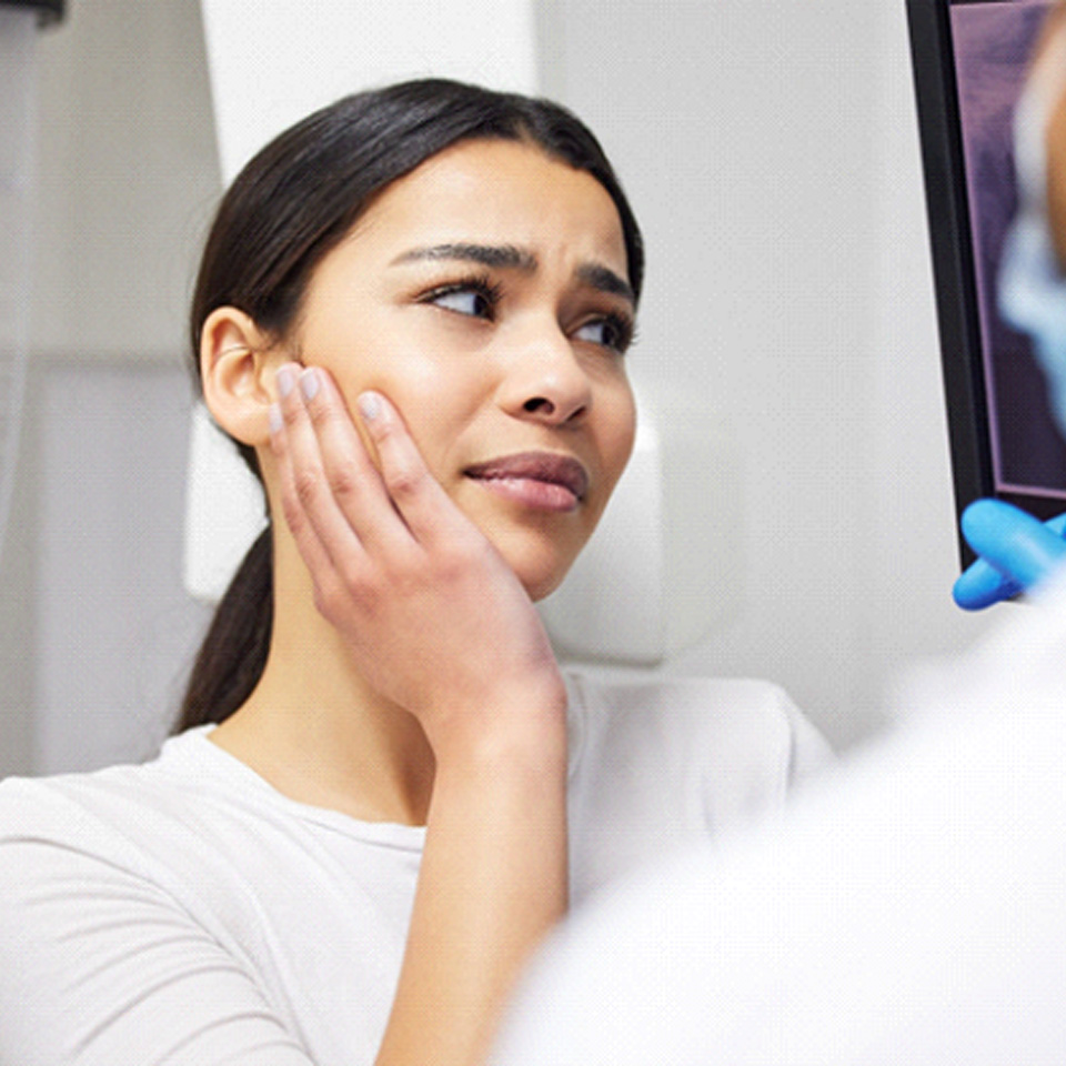 a woman holding her mouth and speaking with a dentist
