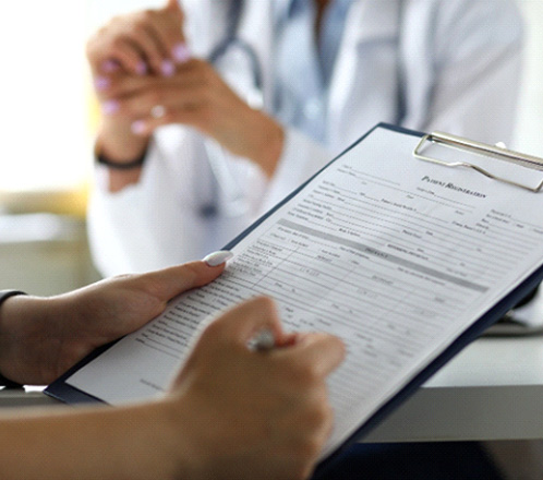 a patient filling out forms that are attached to a black clipboard