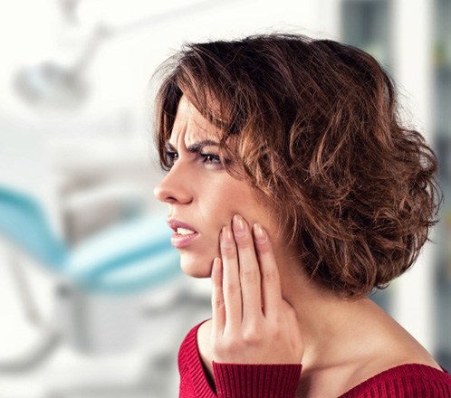 : Woman concerned with her loose dental implant touching her cheek