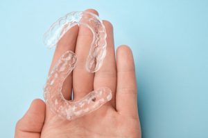 a person holding and caring for their clear aligners