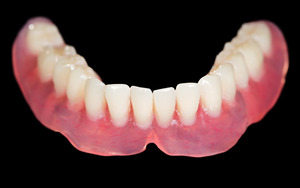 Close-up of full lower dentures on black background