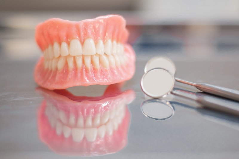 A closeup of dentures sitting on a glass countertop