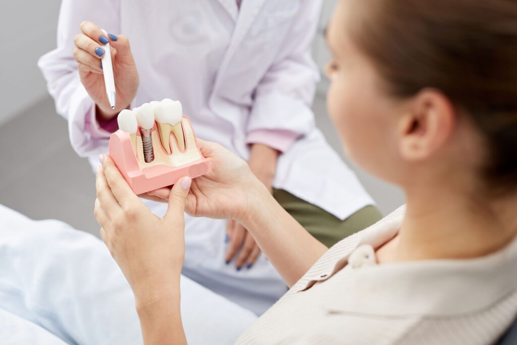 Dentist pointing to sample dental implant held by patient