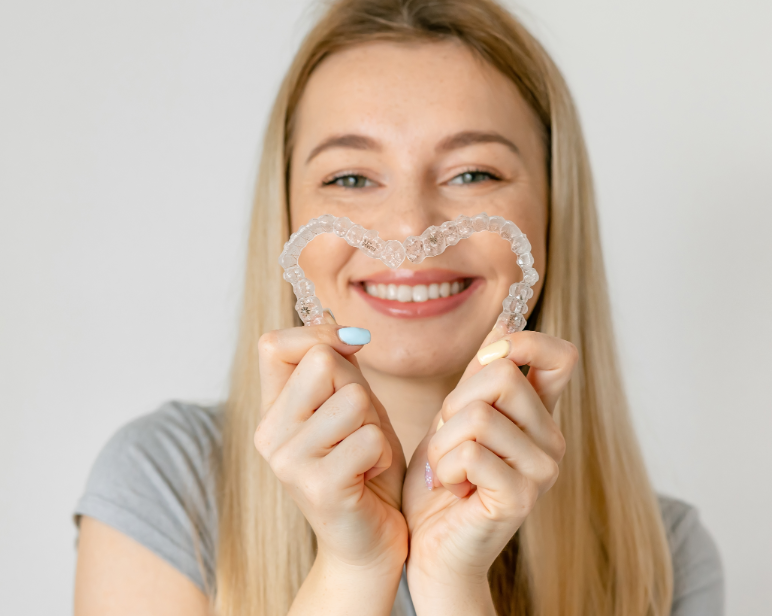 Woman holding clear aligners in heart shape
