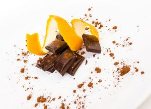 Orange peel and dark chocolate on white surface